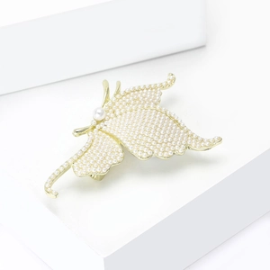 Detailed close-up of a golden butterfly brooch with small white pearls on geometric props