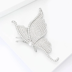 Detail of silver butterfly brooch featuring intricate white pearls on a geometric stand