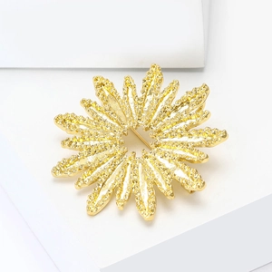 Exquise broche fleur de soleil dorée avec texture martelée sur socle blanc