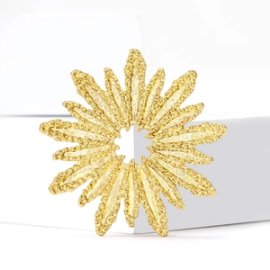 Broche feu d'artifice dorée texture lave sur un support d'exposition blanc minimaliste