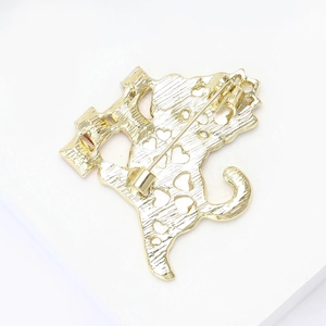 Macro detail of cat brooch back featuring golden brushed metal and heart cutouts