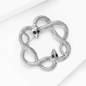 Close-up of silver twin snake brooch showing detailed scale texture and black gem eyes