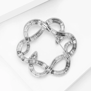 Close-up of silver-tone intertwined snake circle brooch showing the secure metal pin fastening