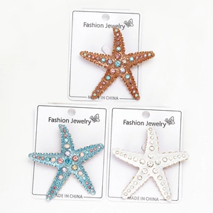 Détail macro de broches étoile de mer avec strass en orange, bleu et blanc sur supports