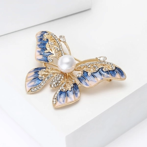 Détail d'une broche papillon avec ailes en émail bleu, strass blancs et perle centrale