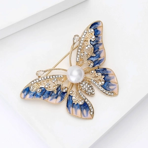 Détails de broche papillon en émail bleu et perles blanches sur un support doré chic