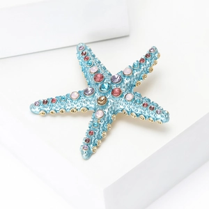 Détail d'une broche étoile de mer tropicale avec strass colorés et émail bleu poli