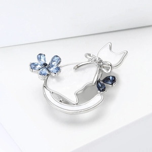 Detailed view of silver cat brooch featuring blue crystal droplets and white enamel