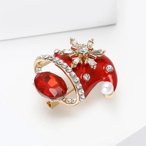 Broche bonnet de Noël en émail rouge avec cristaux sur un fond blanc épuré