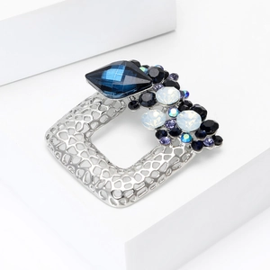 Detailed close-up of hollow square silver brooch featuring blue crystals and rhinestones