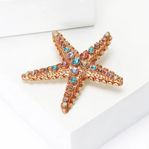Vue détaillée d'une broche étoile de mer avec strass colorés sur métal doré rose