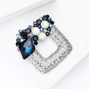 Macro detail of silver alloy square hollow brooch with blue crystals and rhinestones