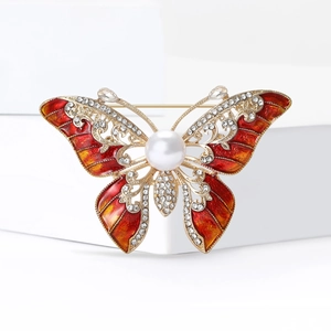 Détail d'une broche papillon de luxe avec émail rouge, perle et cristaux scintillants