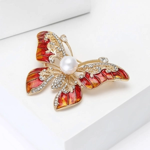 Détail de la broche papillon avec ailes en émail rouge, cristaux et perle centrale