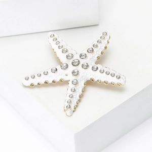 Détail d'une broche étoile de mer élégante avec émail blanc et strass brillants sur métal doré