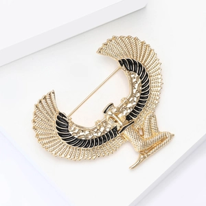 Golden Egyptian Goddess Isis brooch with spreading wings on a white display stand