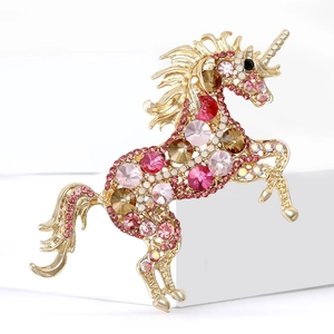 Elegant gold-plated unicorn brooch featuring sparkling colorful rhinestones on a white pedestal