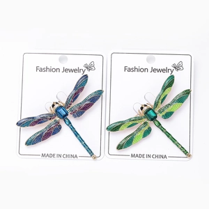 Close-up of enamel dragonfly brooches with blue and green crystals on jewelry cards