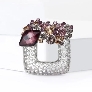 Detailed macro of a hollow alloy brooch featuring purple rhinestones and silver metal finish