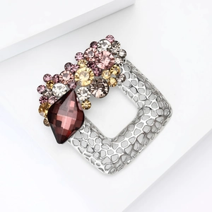 Macro detail of square alloy brooch featuring vintage red gemstone and sparkling rhinestones
