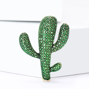 Elegante spilla a cactus dorata con strass verdi scintillanti su un piedistallo bianco