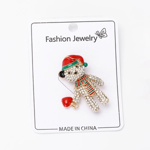 Macro view of Christmas bear brooch with red hat and green striped scarf
