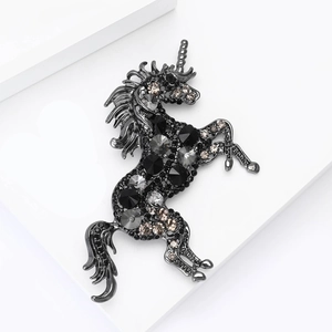 Detailed view of luxury unicorn brooch with black and grey rhinestones on dark metal base