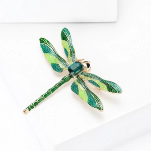 Detail of dragonfly brooch featuring green enamel wings and a deep green gemstone