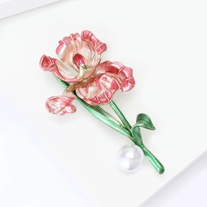 Détail d'une broche fleur de lys en émail rose avec feuilles vertes et perle