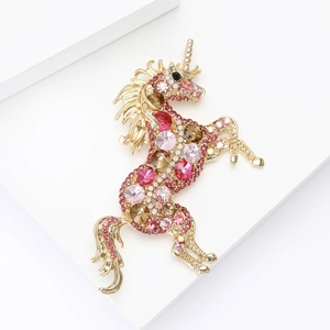 Detail of a luxury unicorn brooch with pink rhinestones on a gold metal base
