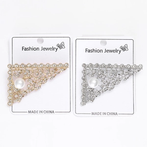 Detailed macro view of silver and gold triangular brooches with rhinestones and pearls