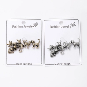 Detail of vintage cat earrings in antique gold and silver finishes on white card