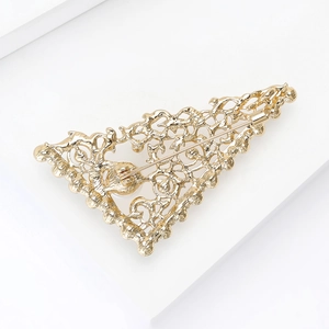 Detail view of a vintage gold hollow triangle brooch with intricate filigree patterns