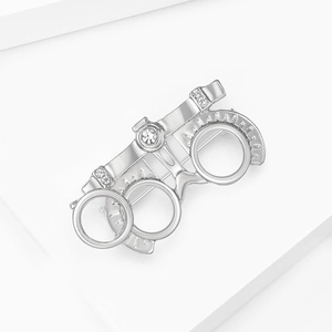 Macro shot of silver metal optometry frame brooch with white rhinestones on white background