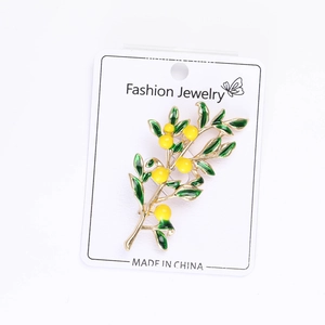 Detail of enamel lemon tree brooch with yellow berries and golden leaves on display card