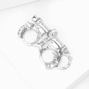 Macro detail of the silver-tone brooch back showing the secure safety pin closure mechanism