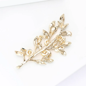 Detail view of the back of a lemon tree brooch showing the golden clasp and pin
