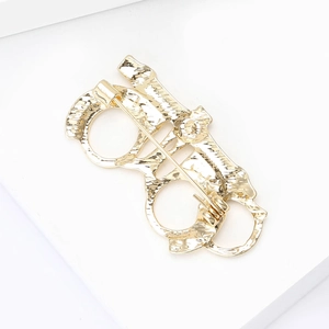 Detailed back view of golden metal brooch with textured finish and safety pin closure
