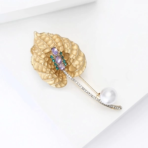 Elegante spilla a giglio dorata con gemme viola e perla bianca su sfondo bianco
