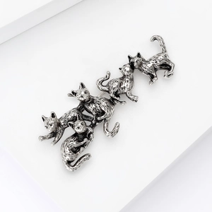 Detail view of vintage silver alloy cat brooch with five cats and embossed textures