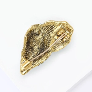 Detailed view of the golden seashell brooch back with safety pin clasp and brushed metal texture