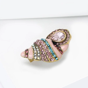 Macro view of shell brooch featuring vintage gold base with pink glaze and inlaid crystals