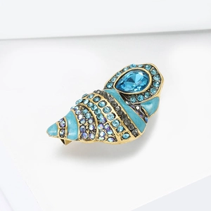 Detailed macro view of gold conch brooch with sky blue enamel and sparkling rhinestones