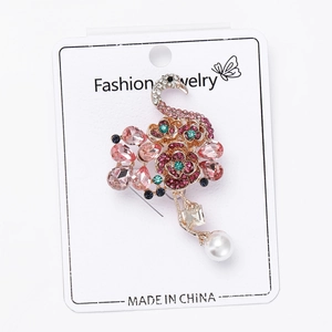 Detalle del broche de flamenco con cristales rosas y perla en tarjeta de joyería