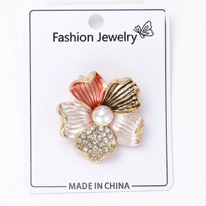 Detail of enamel flower brooch with rhinestones and central pearl on display card