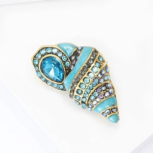 Elegant gold conch brooch with ocean blue enamel and sparkling crystals on white background