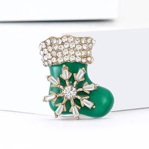 Macro detail of enamel Christmas sock brooch with green finish and sparkling zircons