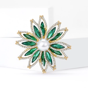 Broche luxueuse fleur de soleil dorée avec cristaux émeraude et perle sur fond blanc