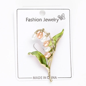 Détail de la broche muguet avec feuilles en émail vert et fleurs en perles nacrées