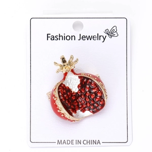 Detail of red enamel pomegranate brooch with sparkling faux gemstone seeds on card